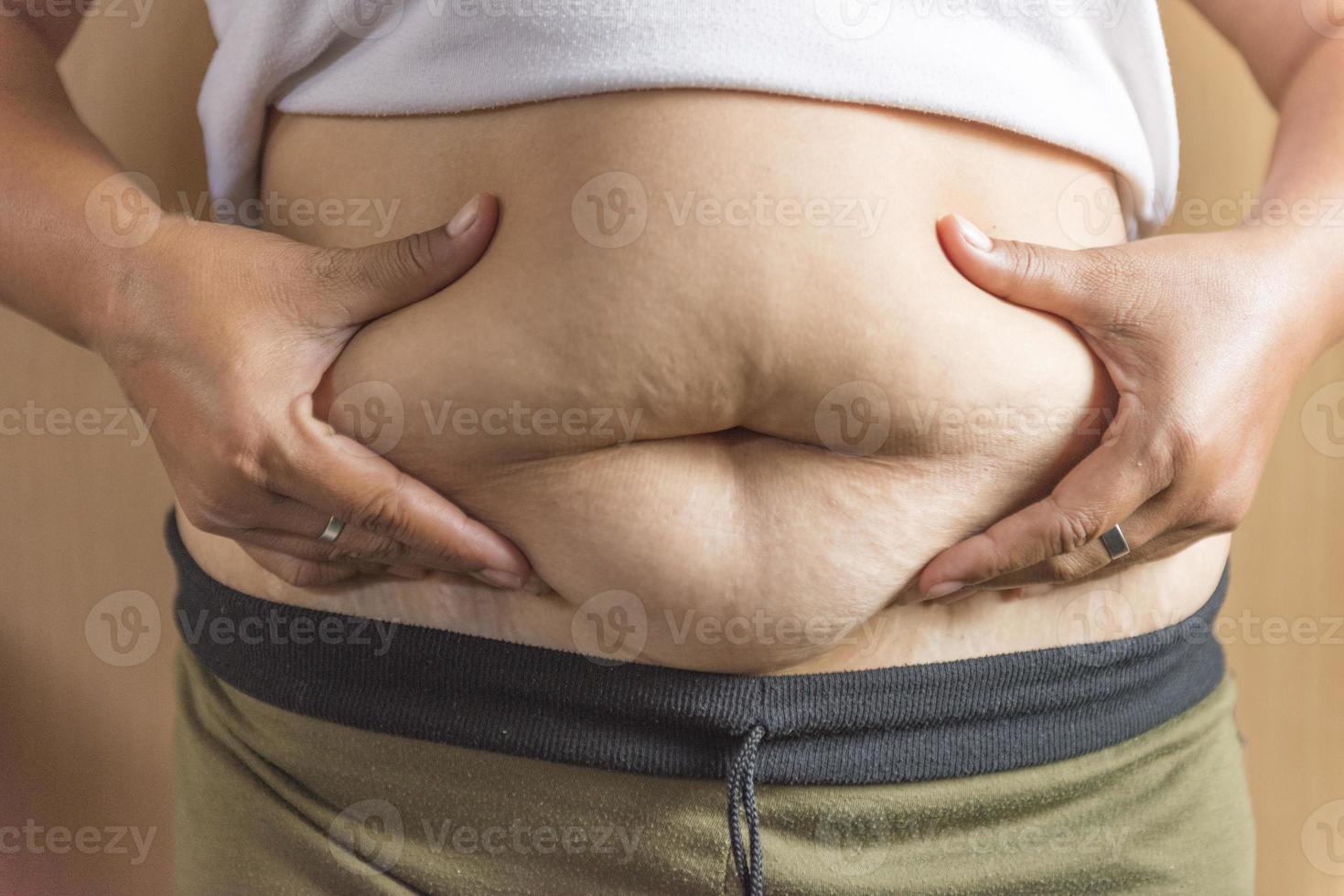 Woman measuring her belly fat with her hands. photo