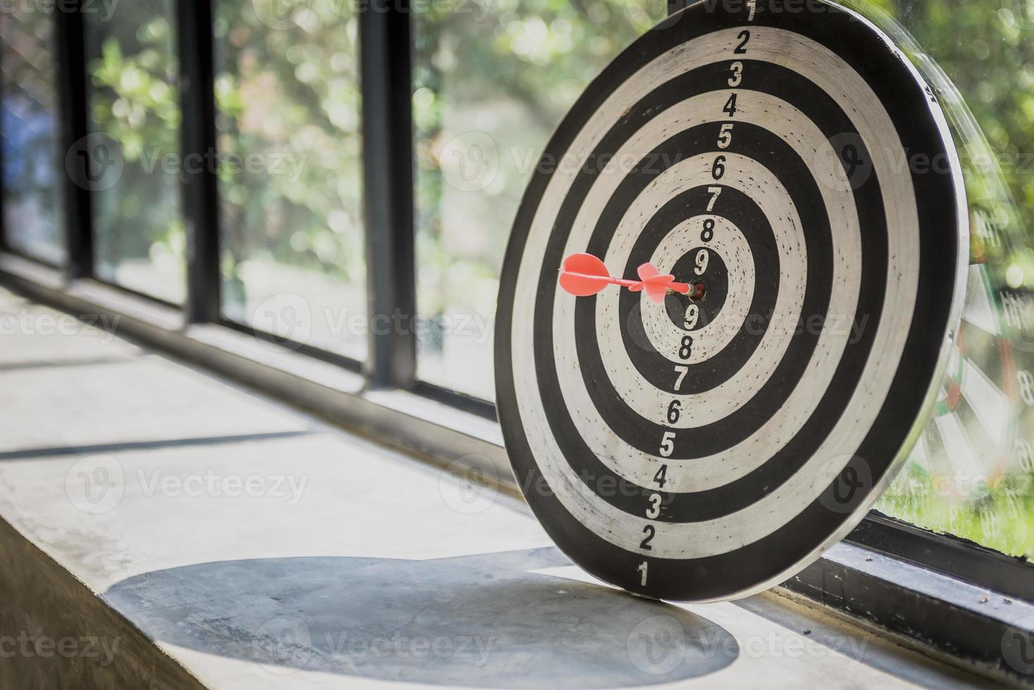 one dart hit it's target on a red background, concept for success, photo