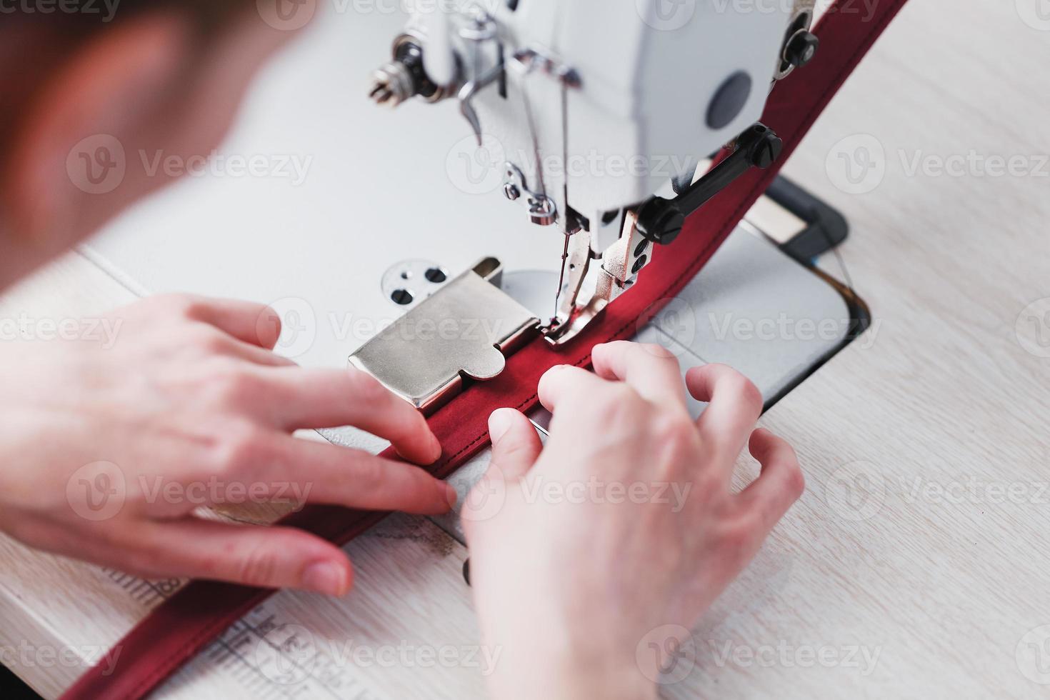 un artesano del cuero produce artículos de cuero en una máquina de coser en su tienda. foto