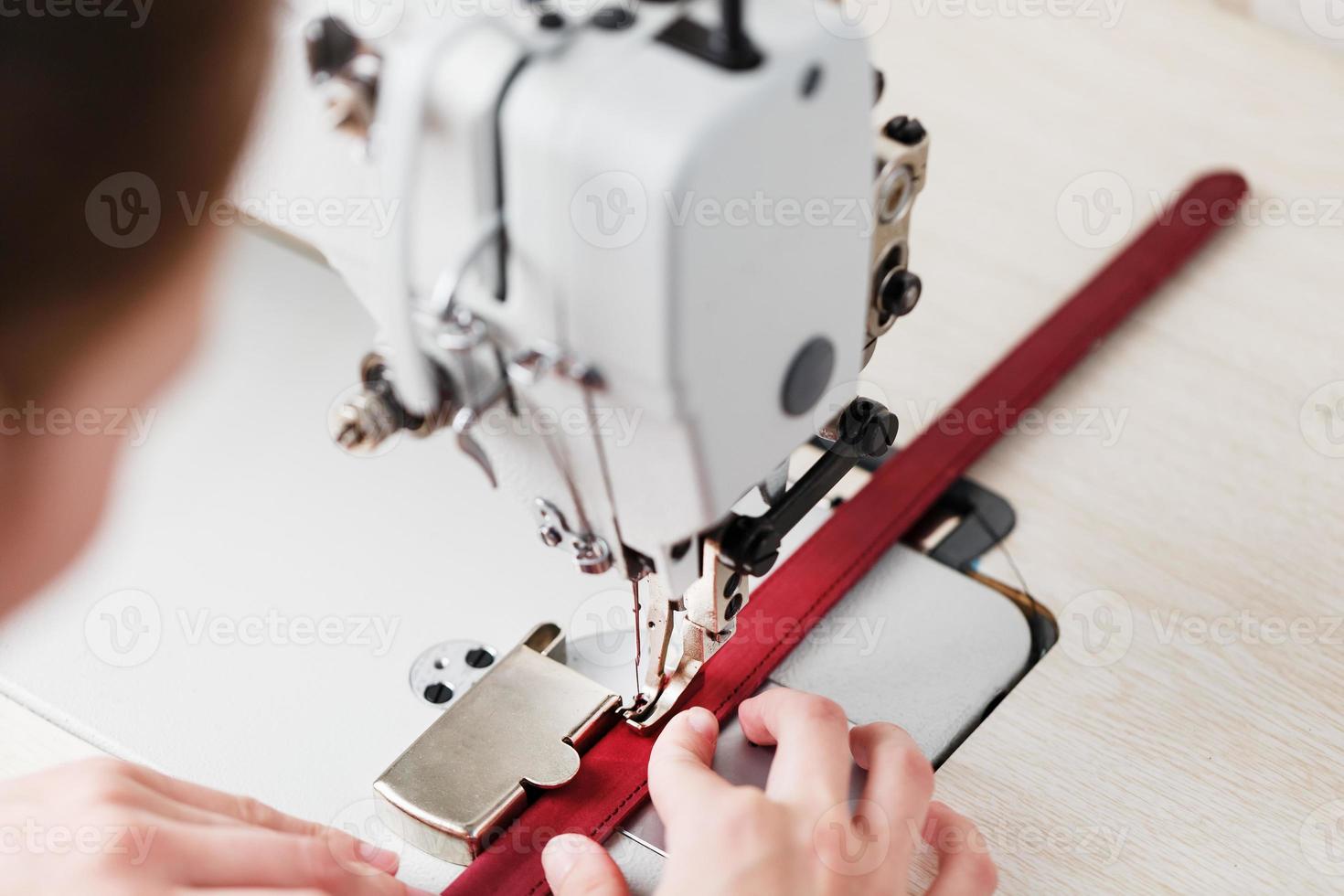 The hands of a master and the needle of a leather product sewing on a sewing machine. Manual work, business. photo