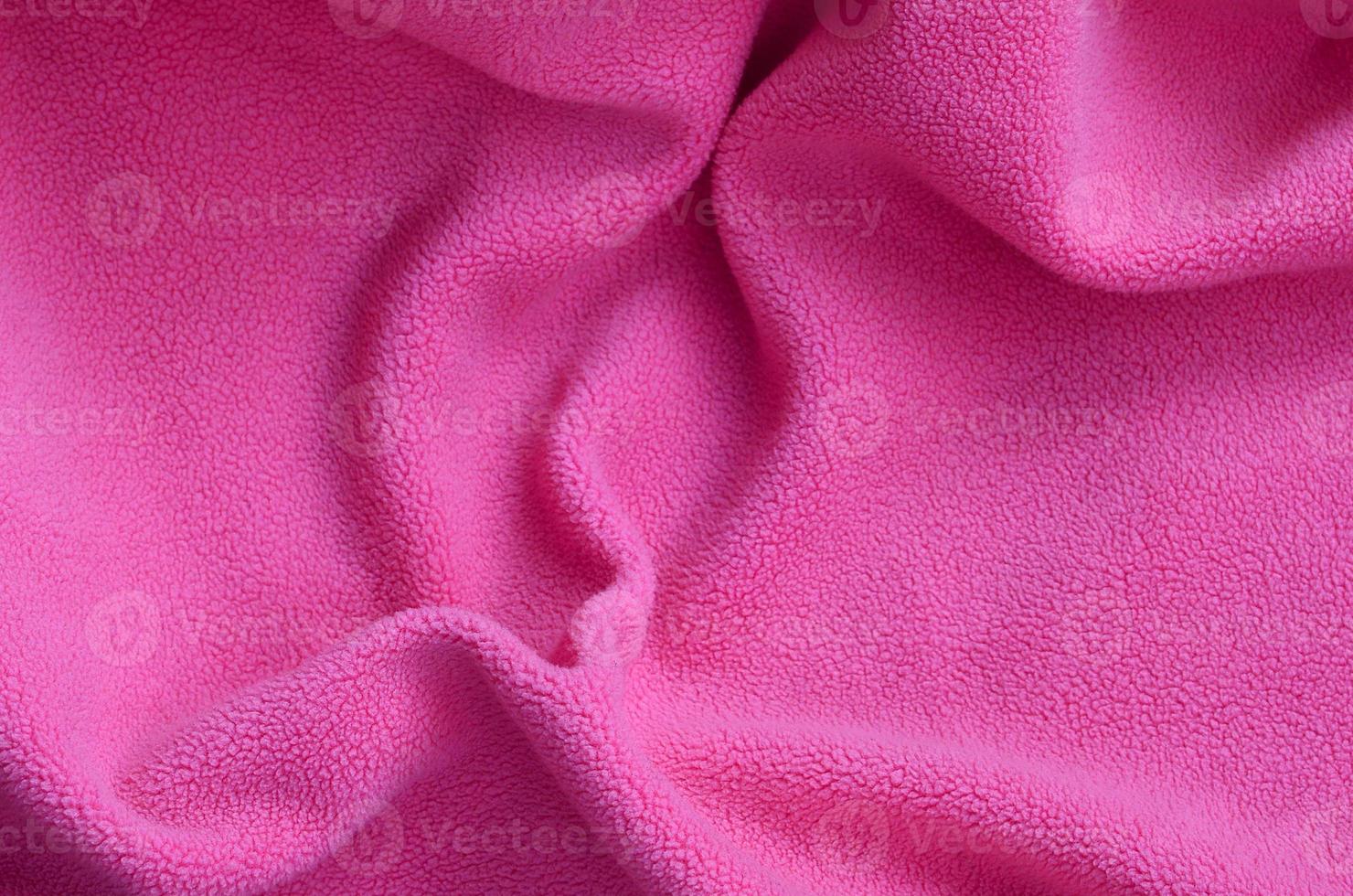 The blanket of furry pink fleece fabric. A background of light pink soft plush fleece material with a lot of relief folds photo