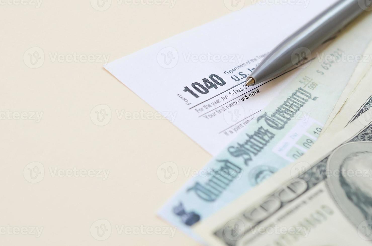 1040 formulario de declaración de impuestos sobre la renta individual con cheque de reembolso y billetes de cien dólares sobre fondo beige foto