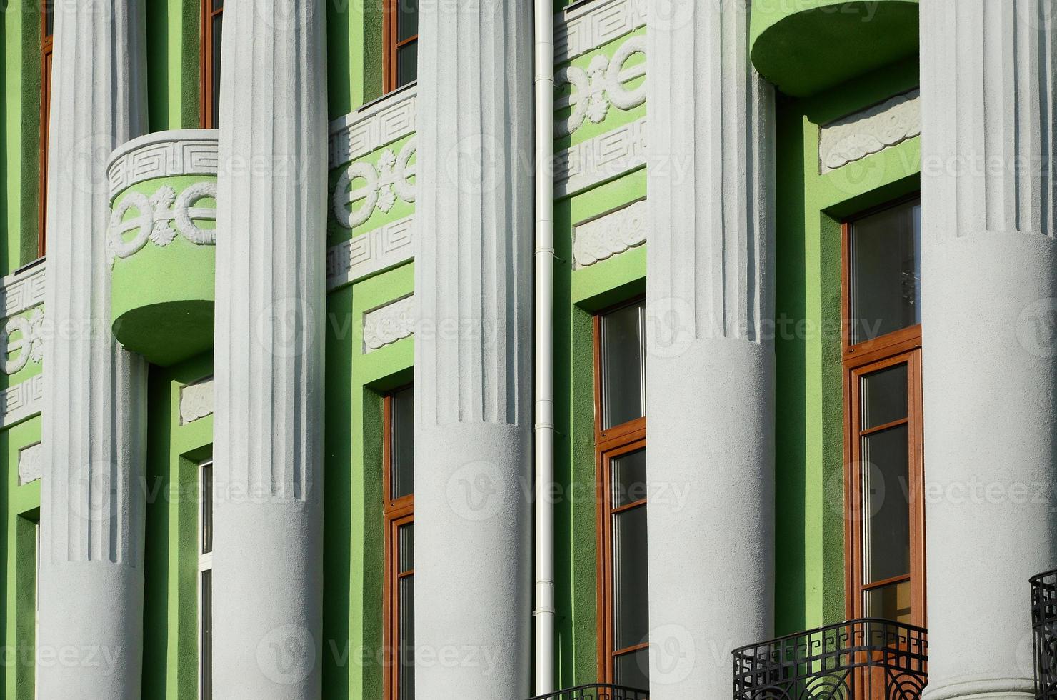 Restored old multi-storey building with antique columns, painted in green photo