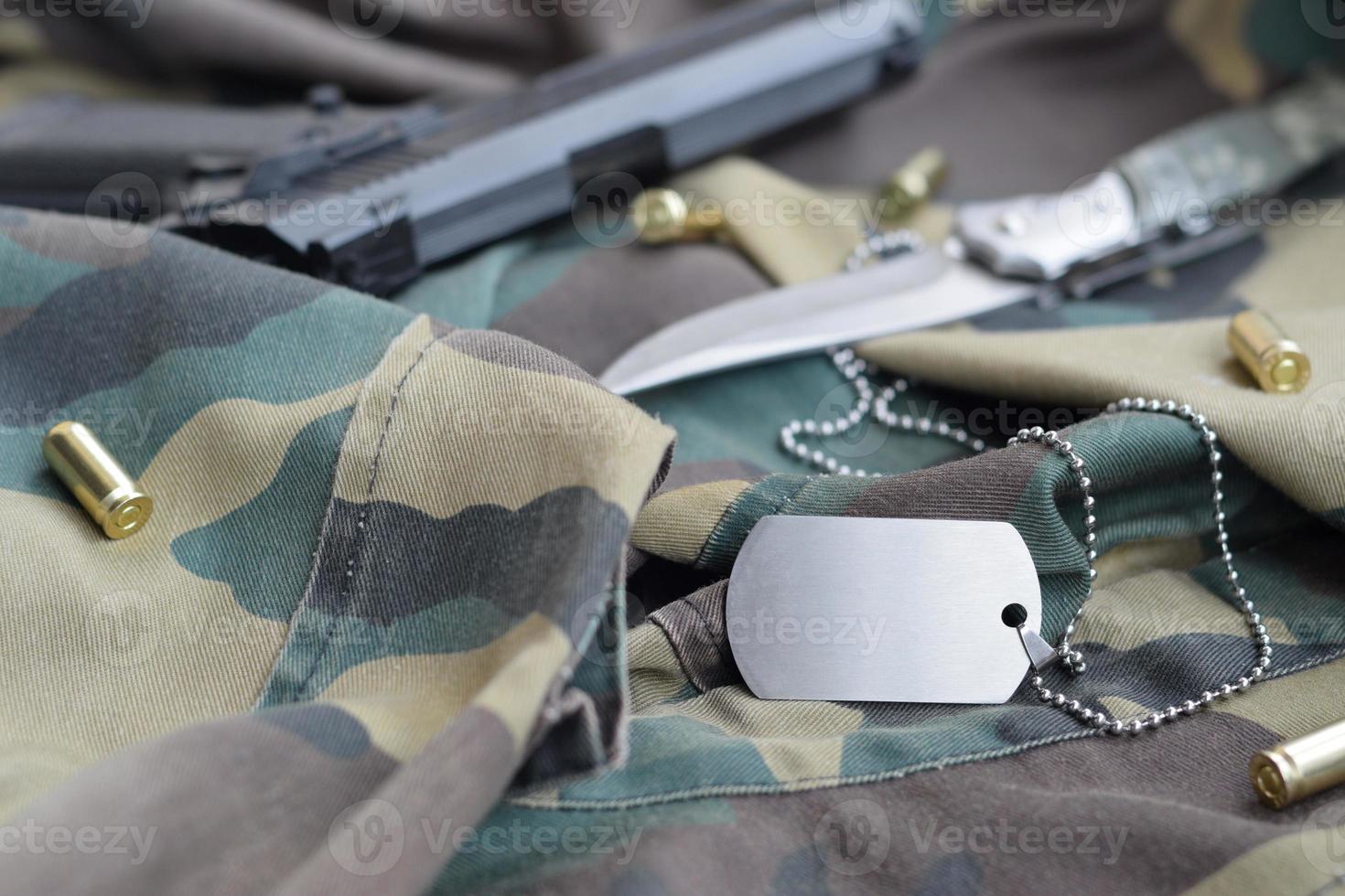 token de etiqueta de perro del ejército con balas de 9 mm y pistola sobre tela verde de camuflaje plegada foto