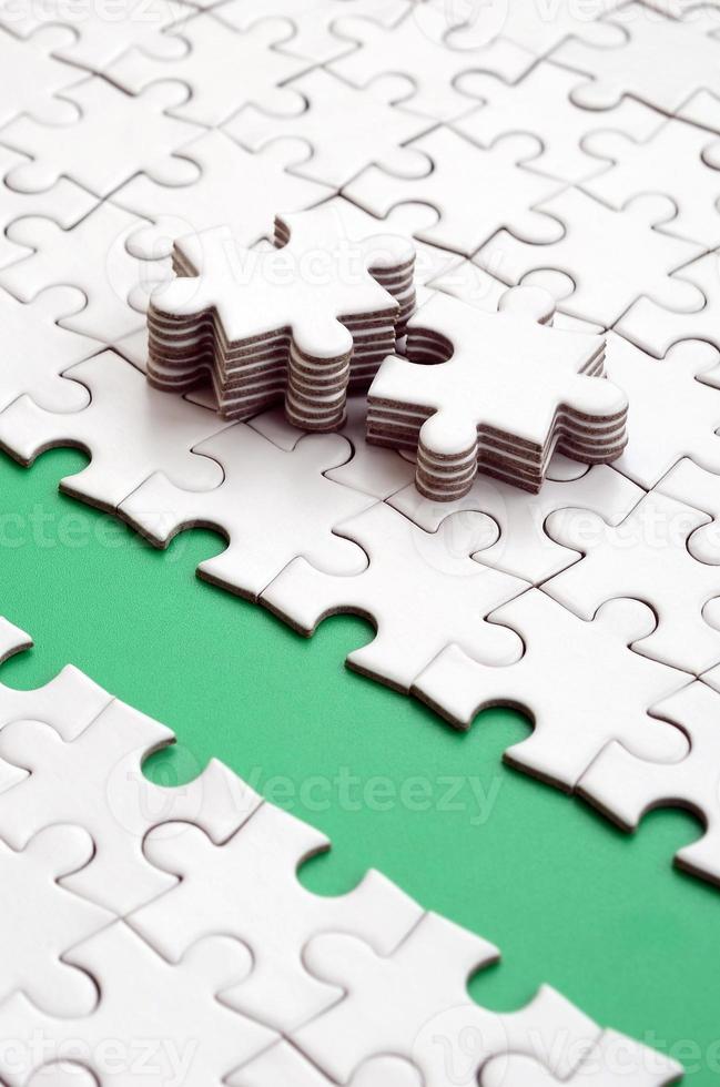 The green path is laid on the platform of a white folded jigsaw puzzle. The missing elements of the puzzle are stacked nearby. Texture image with space for text photo