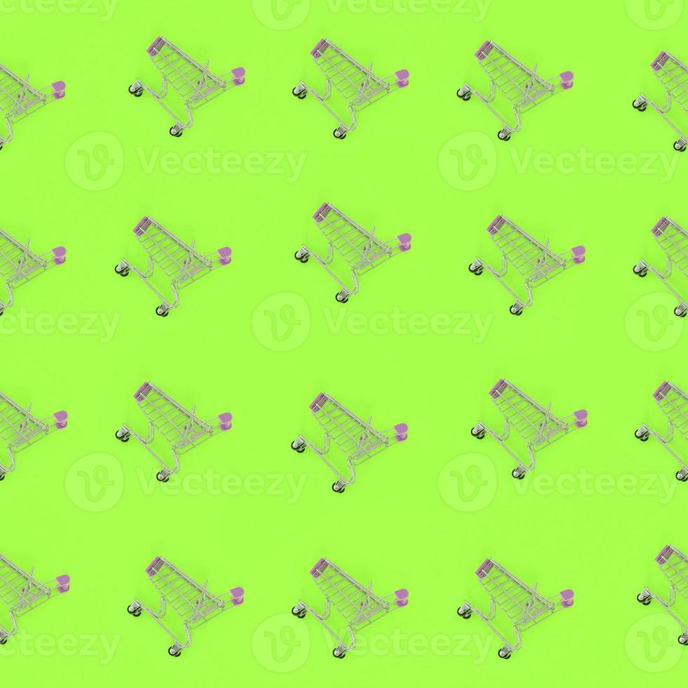 Shopping addiction, shopping lover or shopaholic concept. Many small empty shopping carts perform a pattern on a pastel colored paper background. Flat lay composition, top view photo