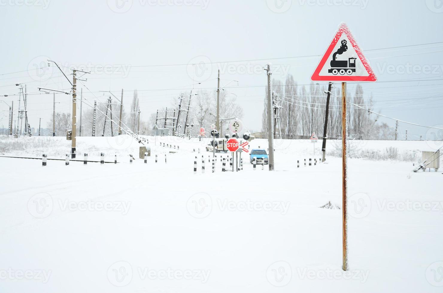 Railway crossing without a barrier with a lot of warning signs in the snowy winter season photo