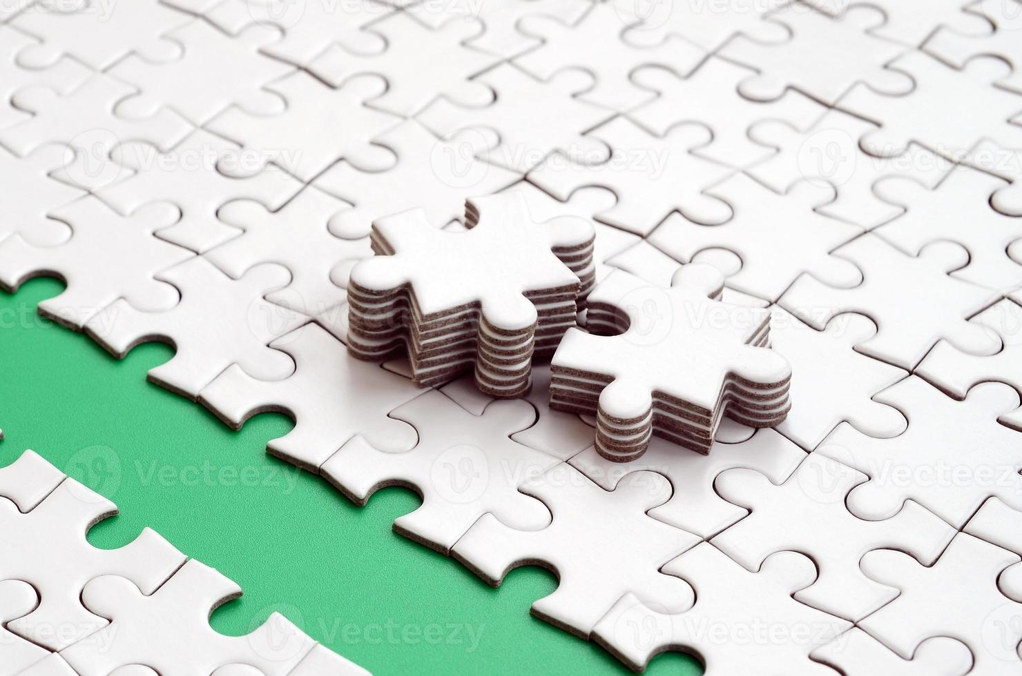 The green path is laid on the platform of a white folded jigsaw puzzle. The missing elements of the puzzle are stacked nearby. Texture image with space for text photo