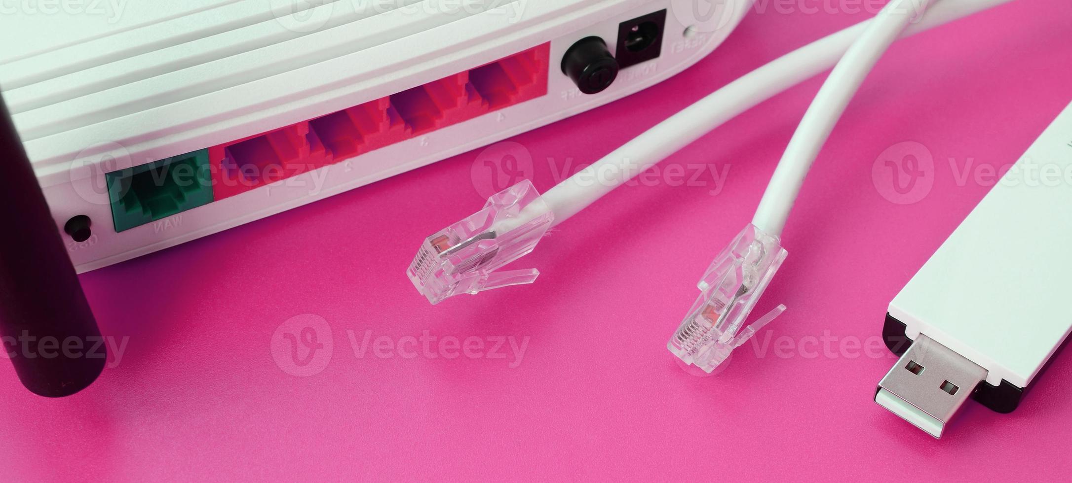 el enrutador de Internet, el adaptador wi-fi usb portátil y los enchufes de cable de Internet se encuentran sobre un fondo rosa brillante. elementos necesarios para internet foto