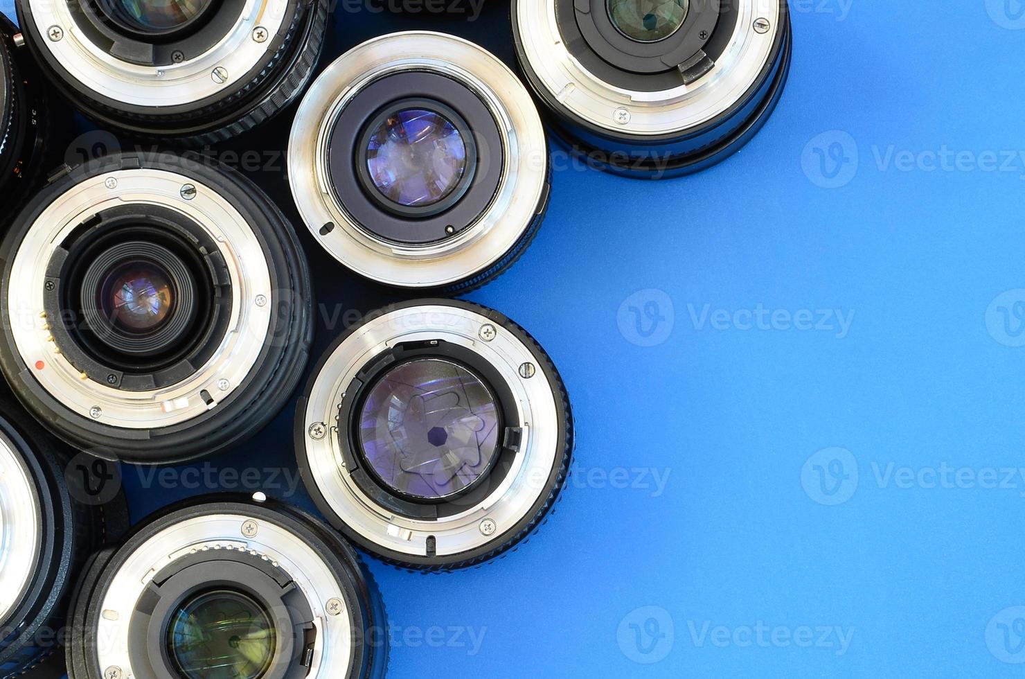 Several photographic lenses lie on a bright blue background. Space for text photo