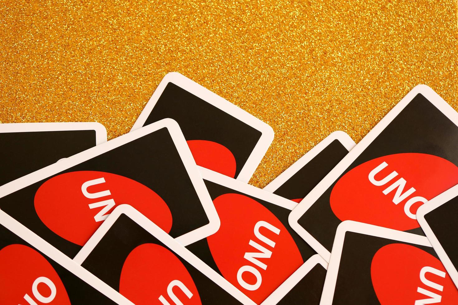 TERNOPIL, UKRAINE - MAY 15, 2022 Many colorful UNO game cards on golden background. UNO is an American shedding-type card game that is played with a specially printed deck photo