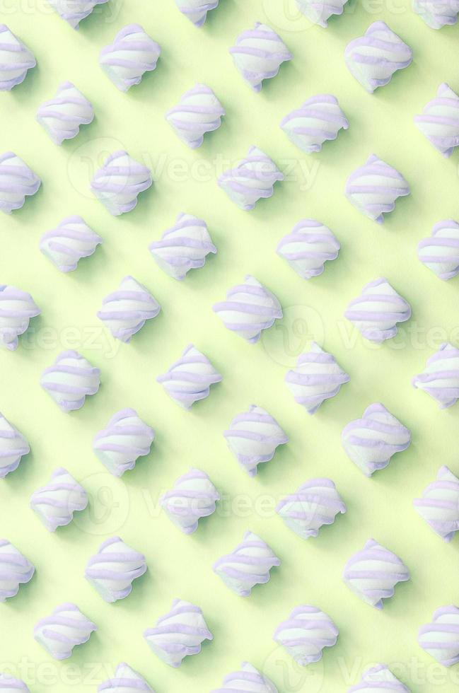 Colorful marshmallow laid out on lime paper background. pastel creative textured pattern photo