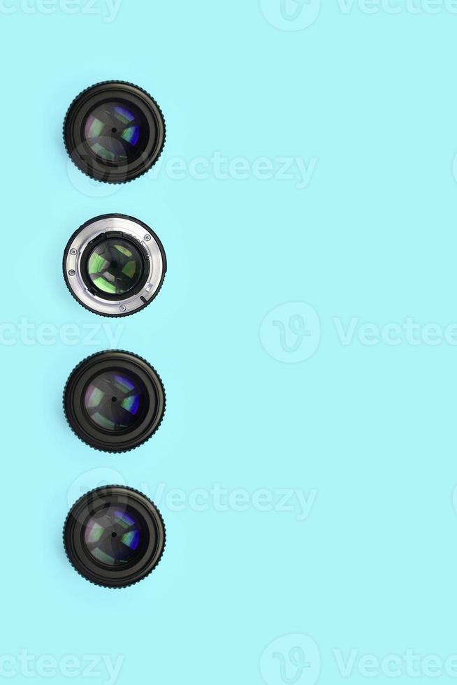 A few camera lenses with a closed aperture lie on texture background of fashion pastel blue color paper photo