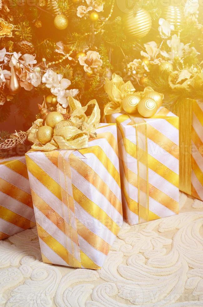 foto de cajas de regalo de lujo bajo el árbol de navidad, decoraciones caseras de año nuevo, envoltorio dorado de regalos de santa, abeto festivo decorado con guirnaldas, adornos y juguetes, celebración tradicional