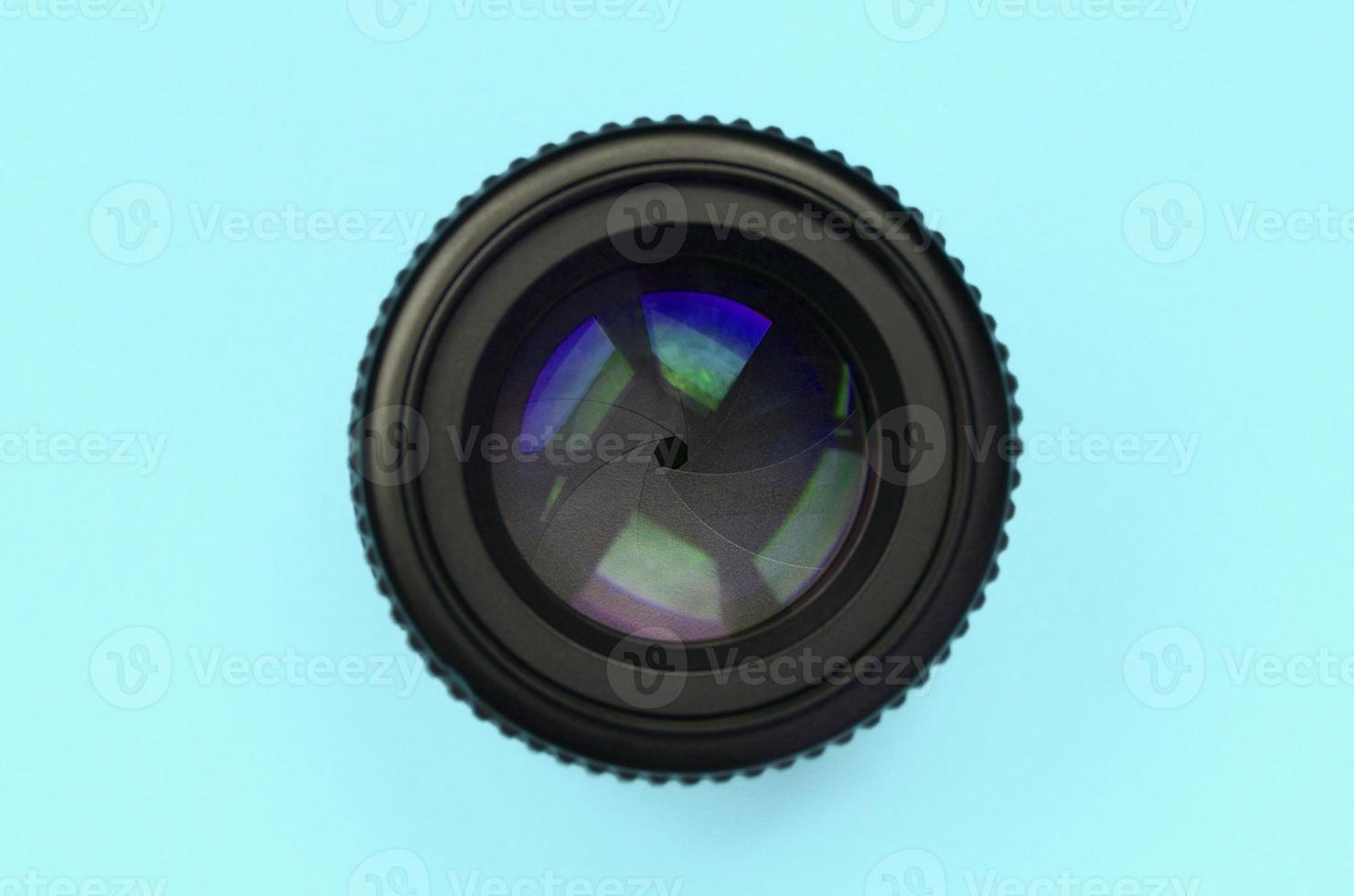 Camera lens with a closed aperture lie on texture background of fashion pastel blue color paper photo