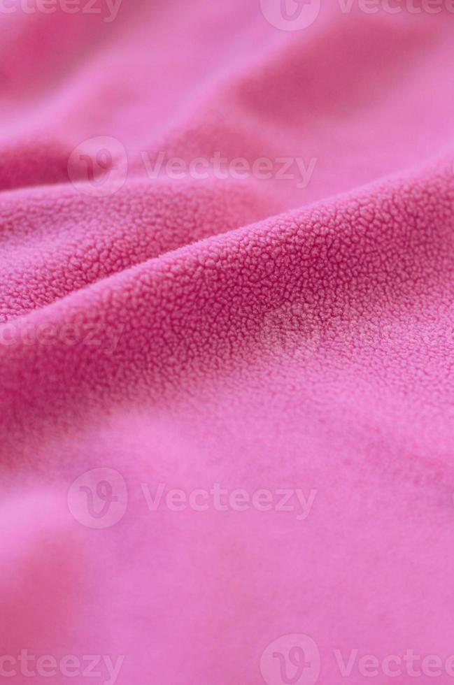 The blanket of furry pink fleece fabric. A background of light pink soft plush fleece material with a lot of relief folds photo