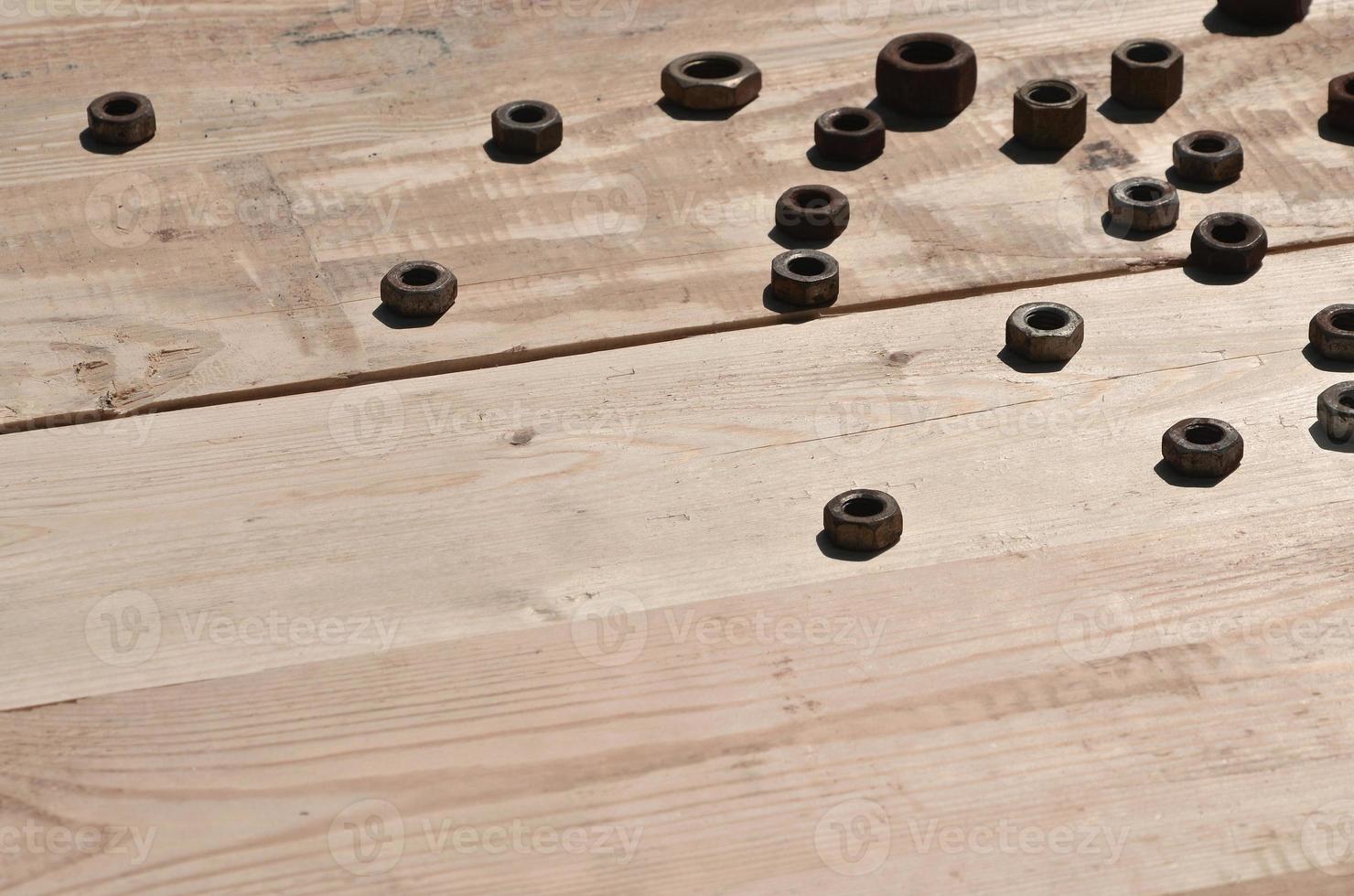 A few rusty nuts lies on a wooden table in a workshop photo