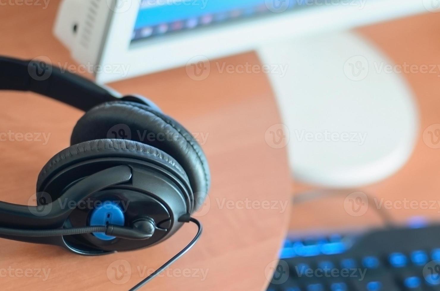 Big black headphones lie on the wooden desktop of the sound designer photo