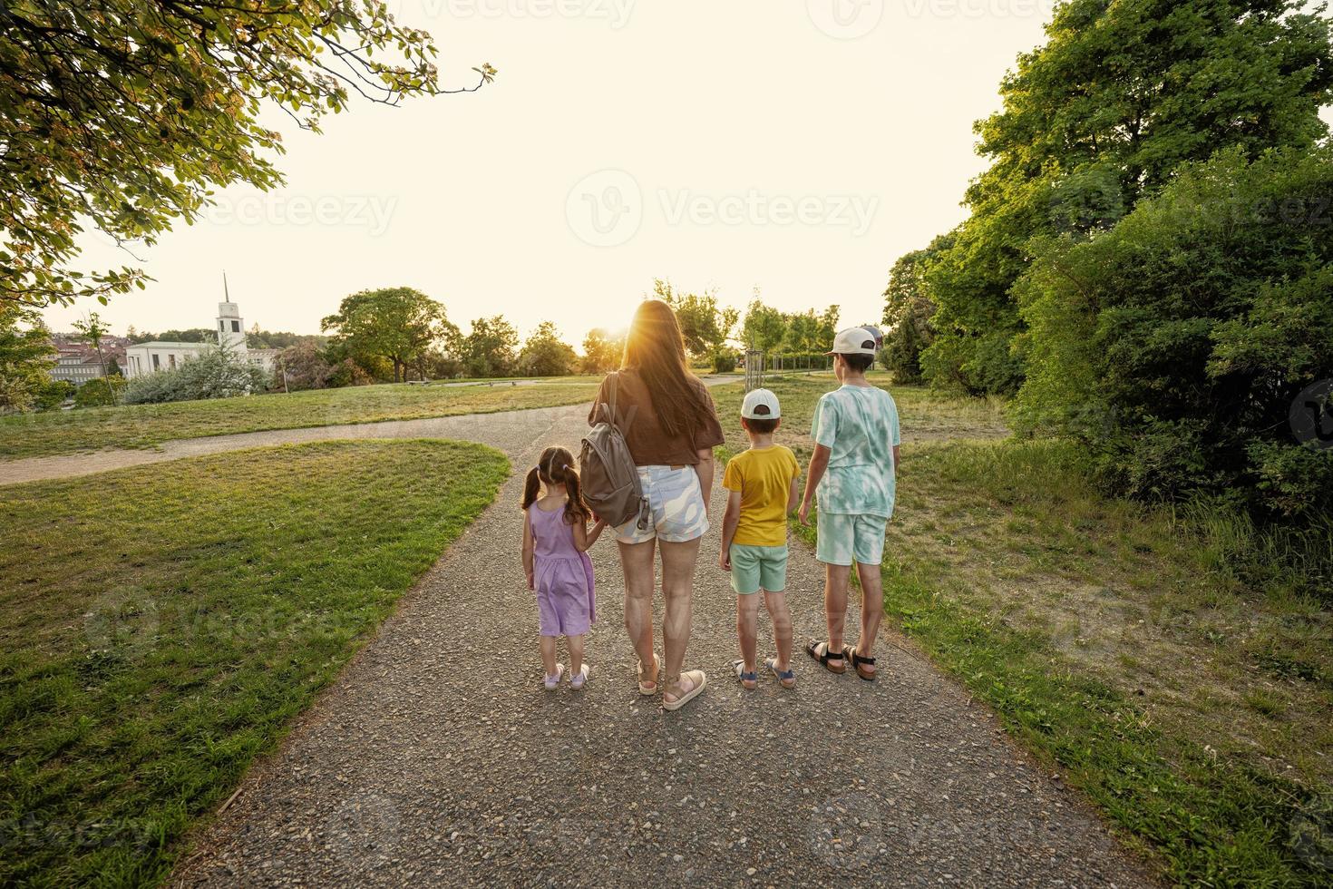 Back of mother with three kids in sundown at park. photo