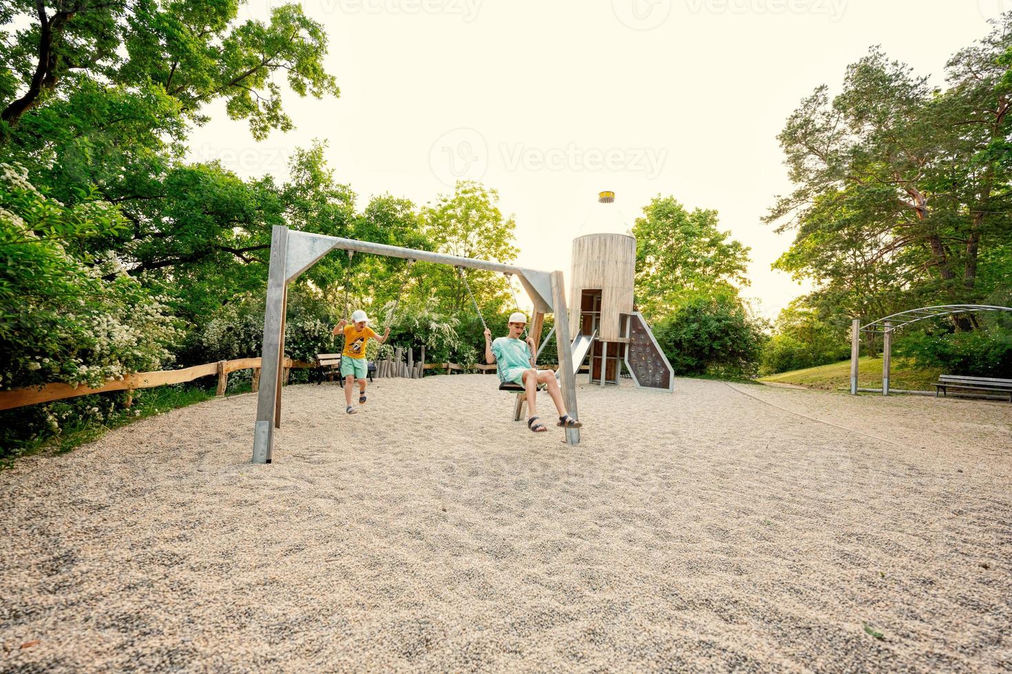 dos hermanos se balancean en un juego de juegos para niños en un parque público. foto