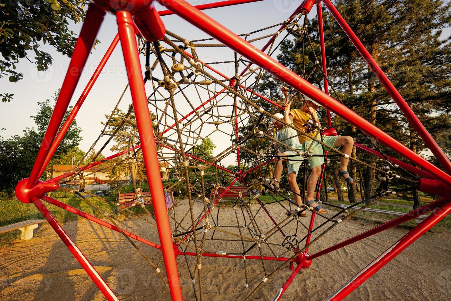 Brothers play in rope polyhedron climb at playground outdoor. photo