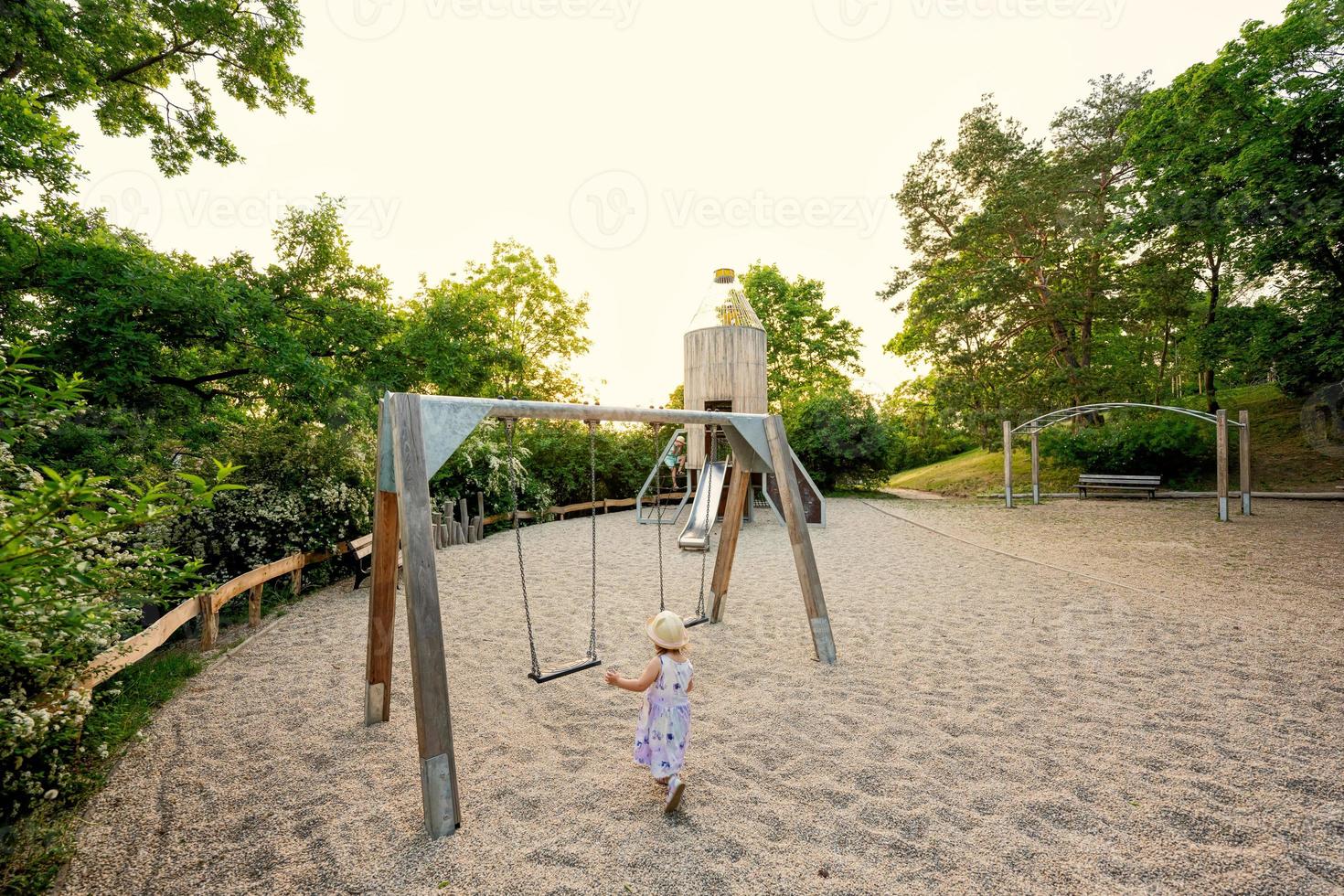 Baby girl swing in children's playground toy set in public park. photo