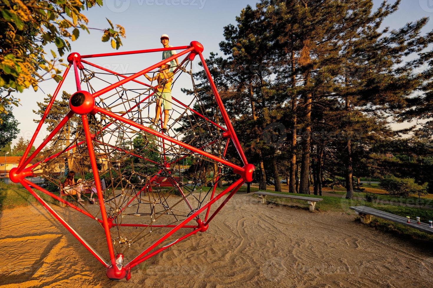 Brothers play in rope polyhedron climb at playground outdoor. photo