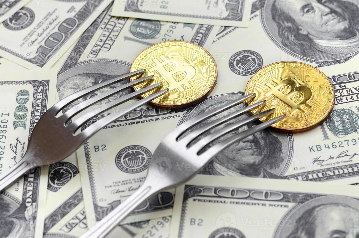 Bitcoin getting New Hard Fork Change, Physical Golden Crytocurrency Coin under the fork on the dollars background. Blockchain Transaction System Crisis Concept photo