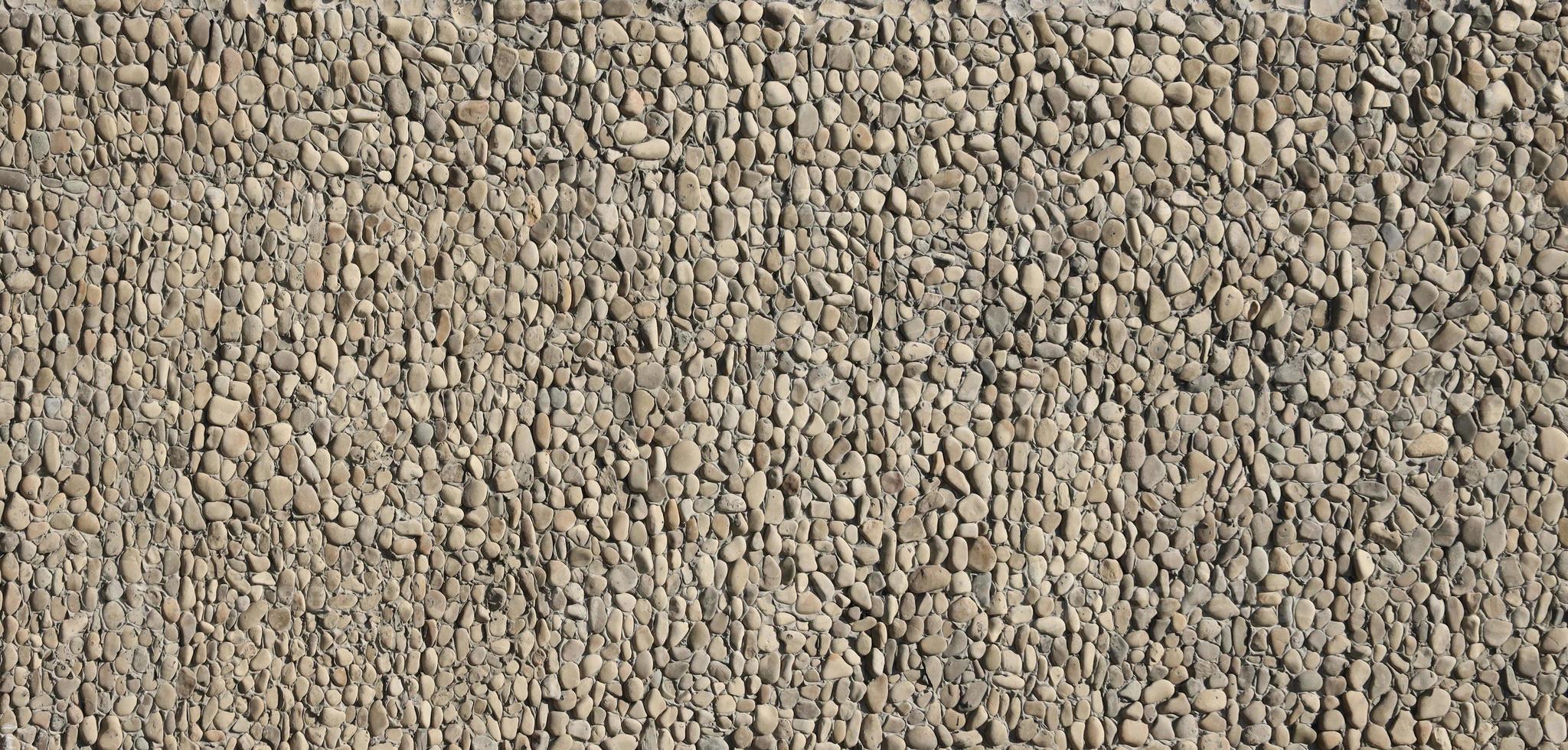Texture of a stone wall with small round pebble stones. Part of a stone wall as a background or texture photo