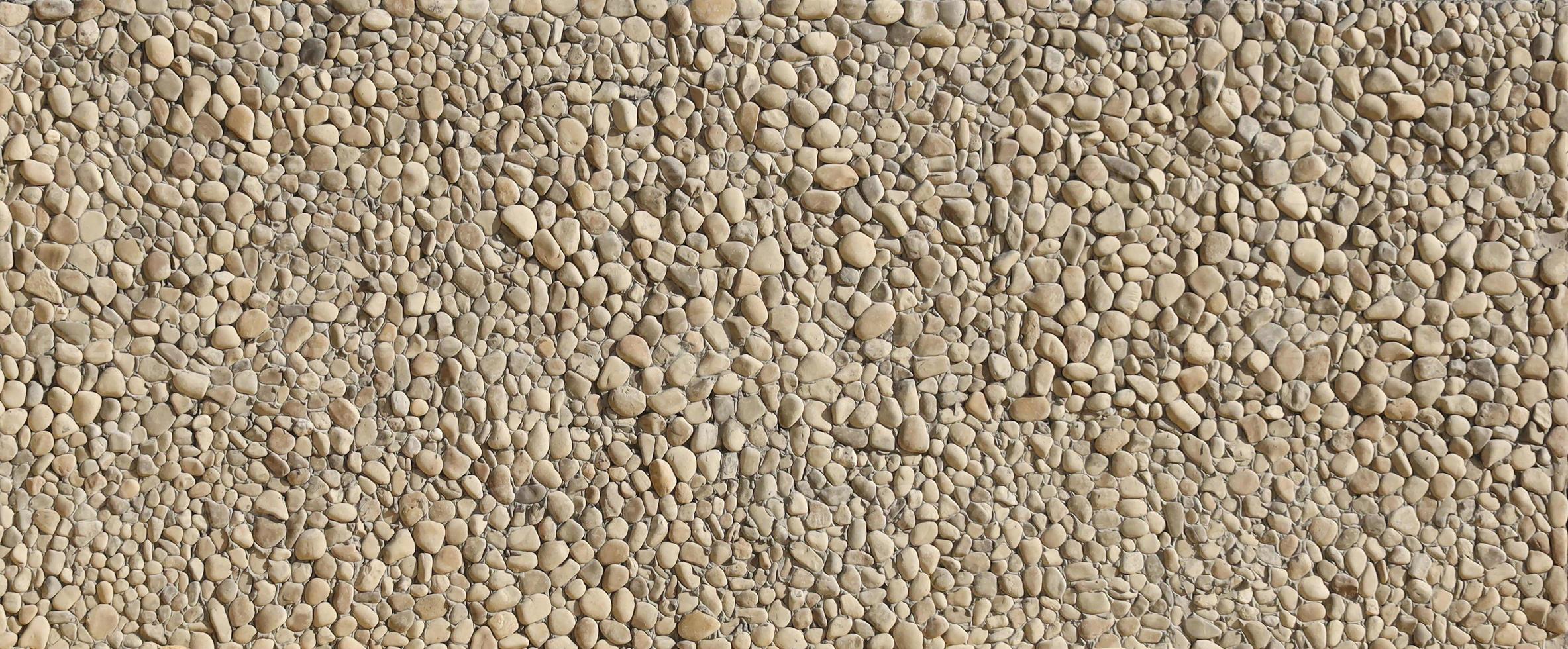Texture of a stone wall with small round pebble stones. Part of a stone wall as a background or texture photo