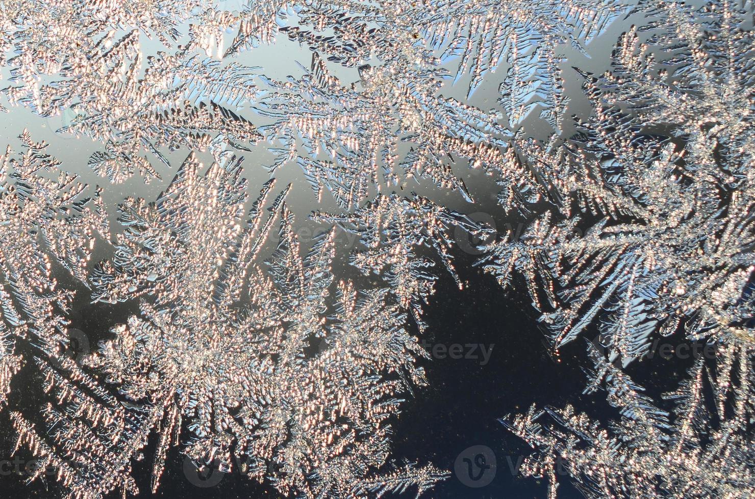 Snowflakes frost rime macro on window glass pane photo