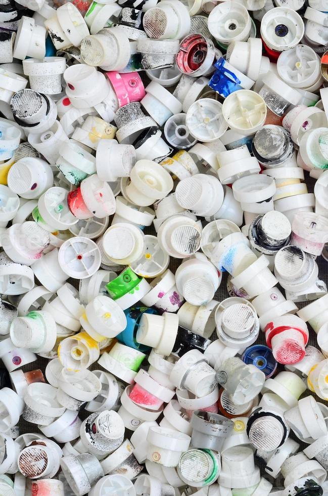 A pattern of many used and soiled nozzles from spray cans with aerosol paint. Background texture of the street art of drawing graffiti on the walls photo