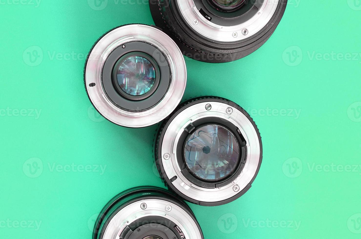 Several photographic lenses lie on a bright turquoise background. Copy space photo