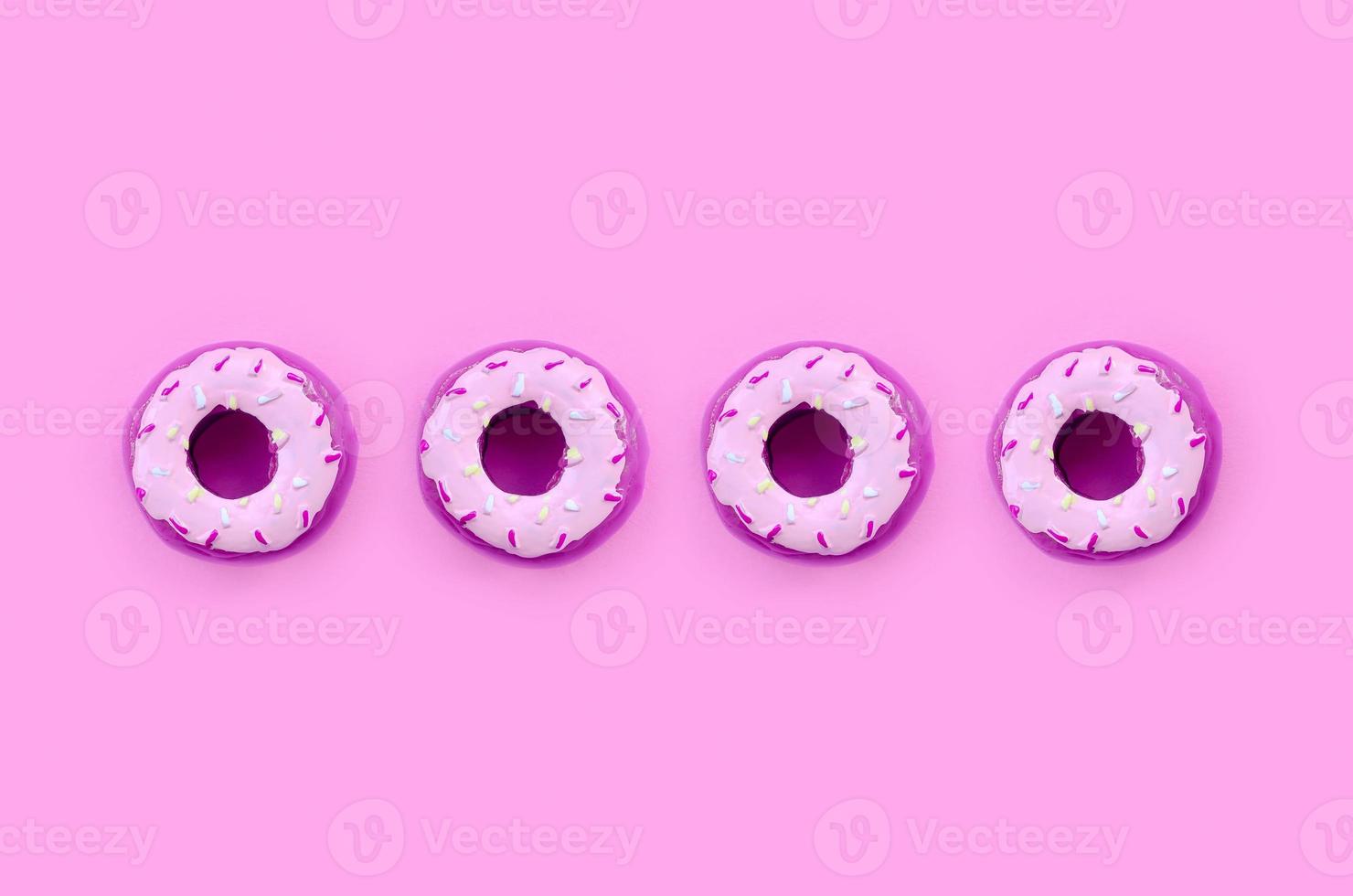 Many small plastic donuts lies on a pastel colorful background. Flat lay minimal pattern. Top view photo