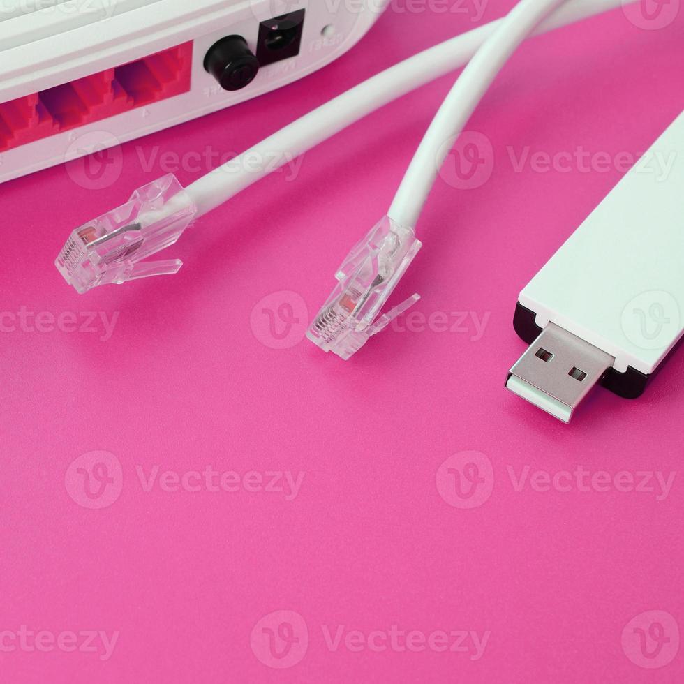 el enrutador de Internet, el adaptador wi-fi usb portátil y los enchufes de cable de Internet se encuentran sobre un fondo rosa brillante. elementos necesarios para internet foto
