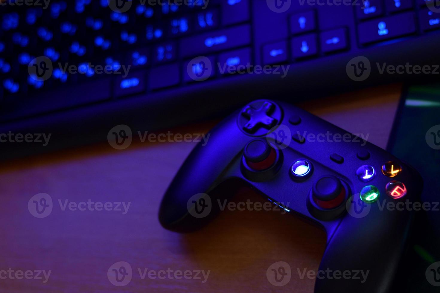 Modern gamepad lies with keyboard on table in dark playroom scene. Video game challenges and competitions concept photo