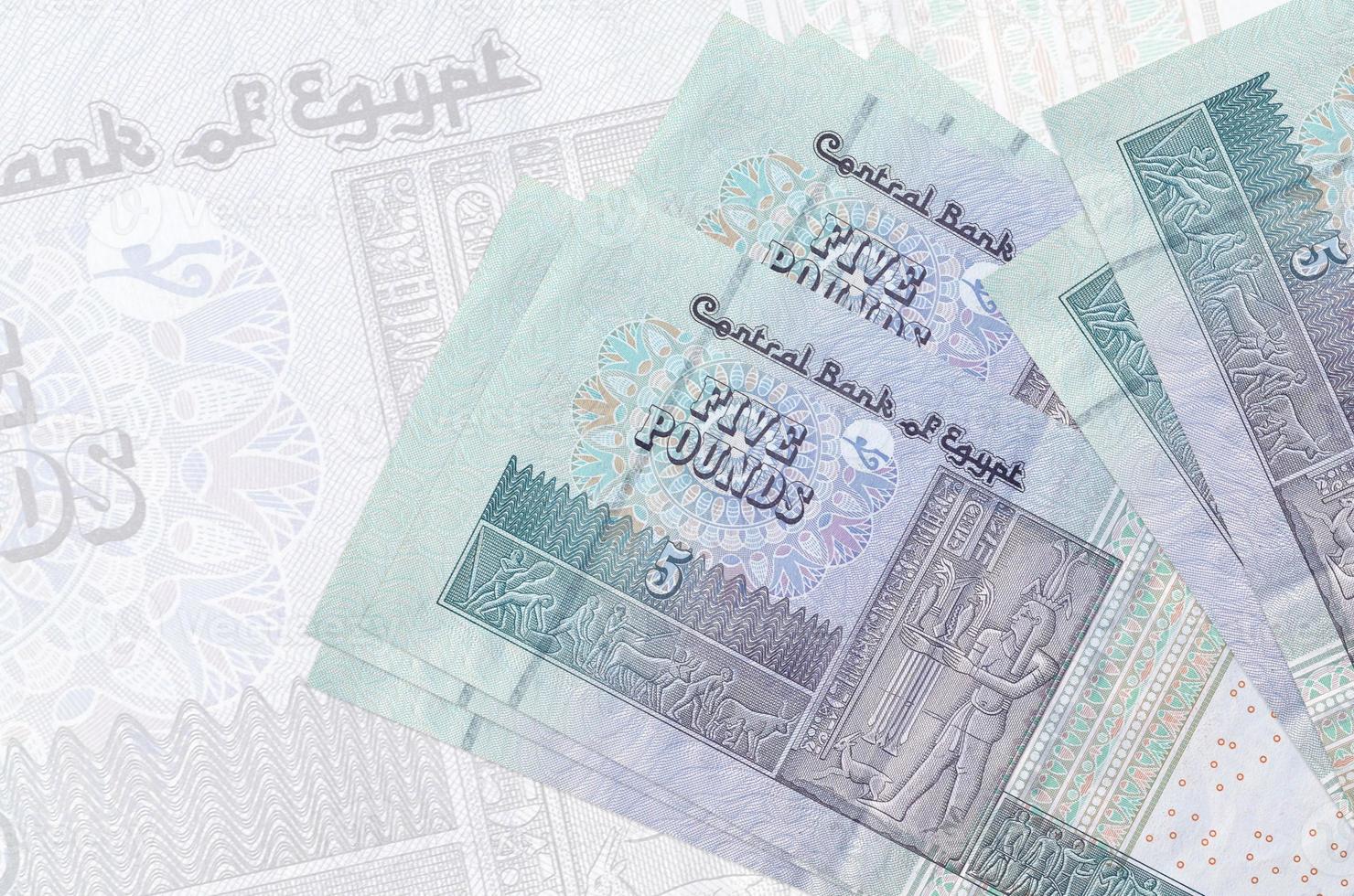 5 Egyptian pounds bills lies in stack on background of big semi-transparent banknote. Abstract presentation of national currency photo