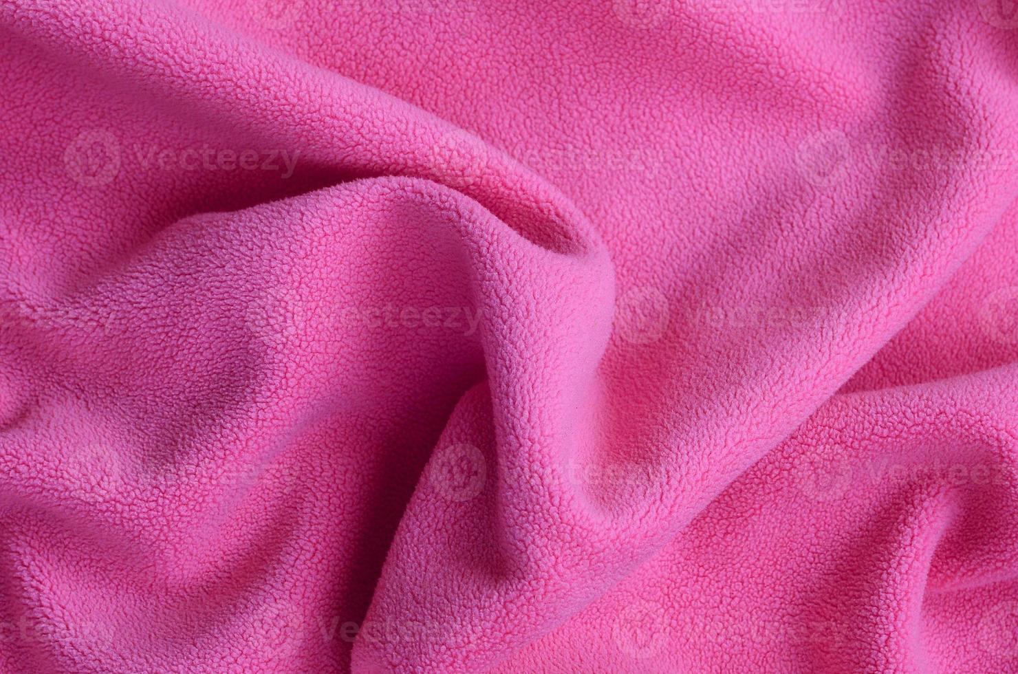 The blanket of furry pink fleece fabric. A background of light pink soft plush fleece material with a lot of relief folds photo