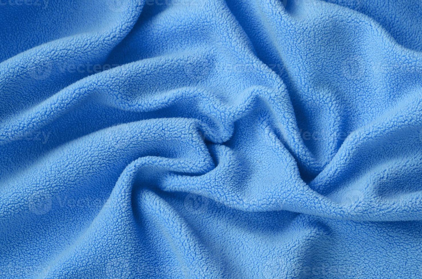 The blanket of furry blue fleece fabric. A background of light blue soft plush fleece material with a lot of relief folds photo