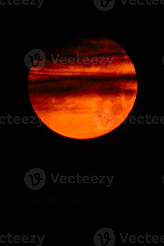 Flower blood full moon in May shortly before the lunar eclipse with red color and passing clouds photo