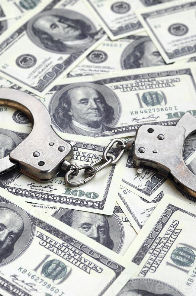 Police handcuffs lie on a lot of dollar bills. The concept of illegal possession of money, illegal transactions with US dollars. Economic Crime photo