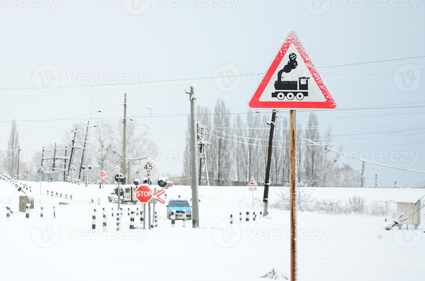 Railway crossing without a barrier with a lot of warning signs in the snowy winter season photo