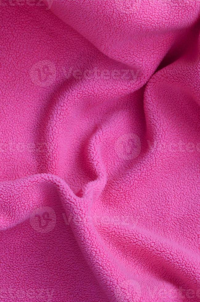 The blanket of furry pink fleece fabric. A background of light pink soft plush fleece material with a lot of relief folds photo