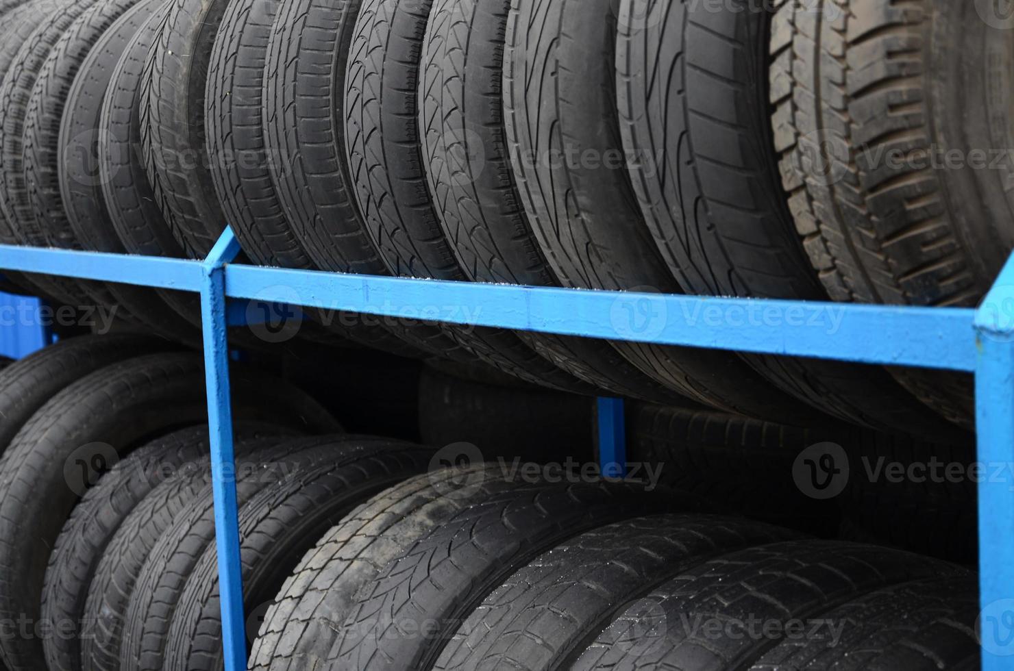 Rack with variety of car tires in automobile store. Many black tires. Tire stack background. Selective focus photo