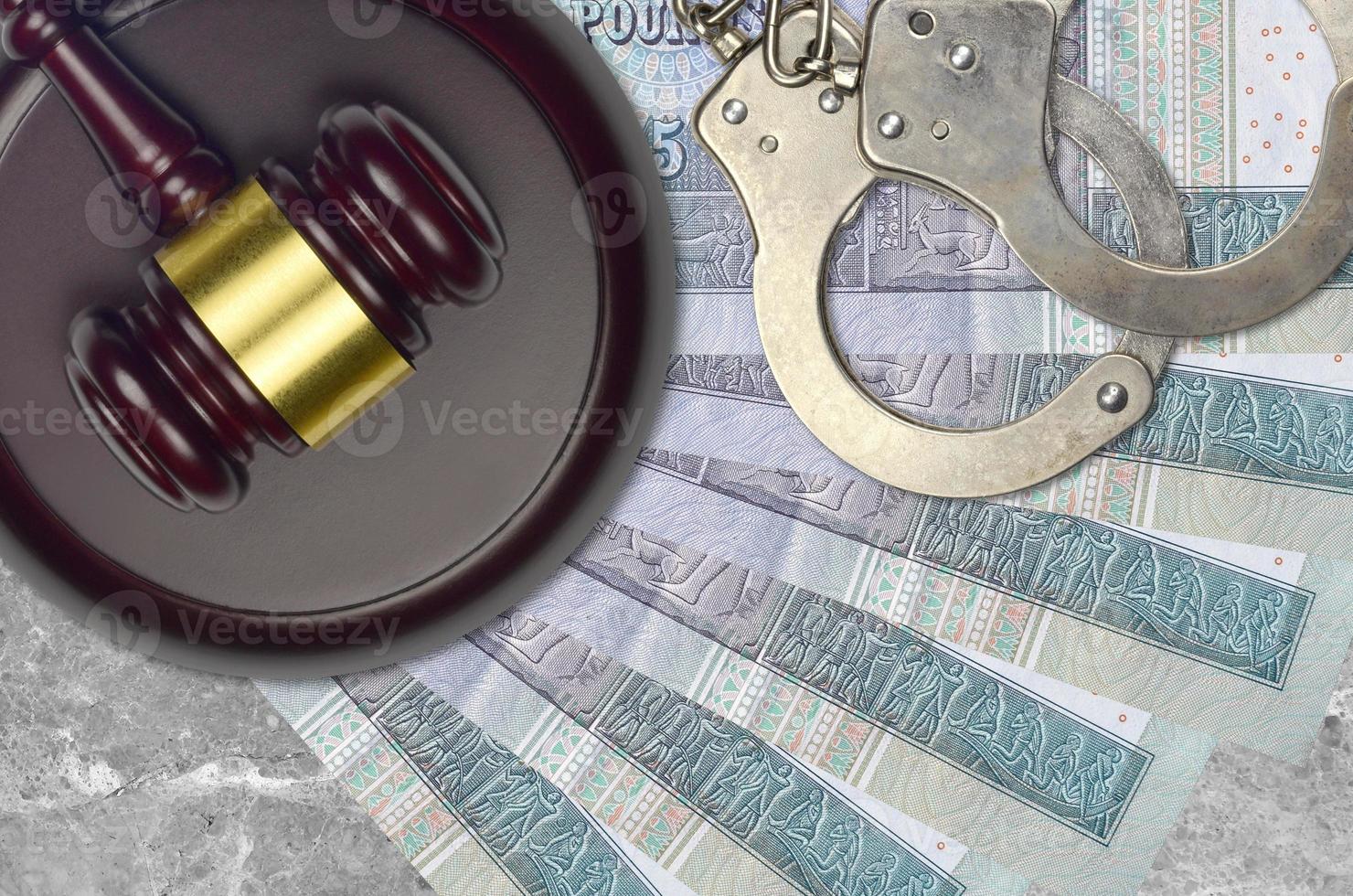 5 Egyptian pounds bills and judge hammer with police handcuffs on court desk. Concept of judicial trial or bribery. Tax avoidance photo