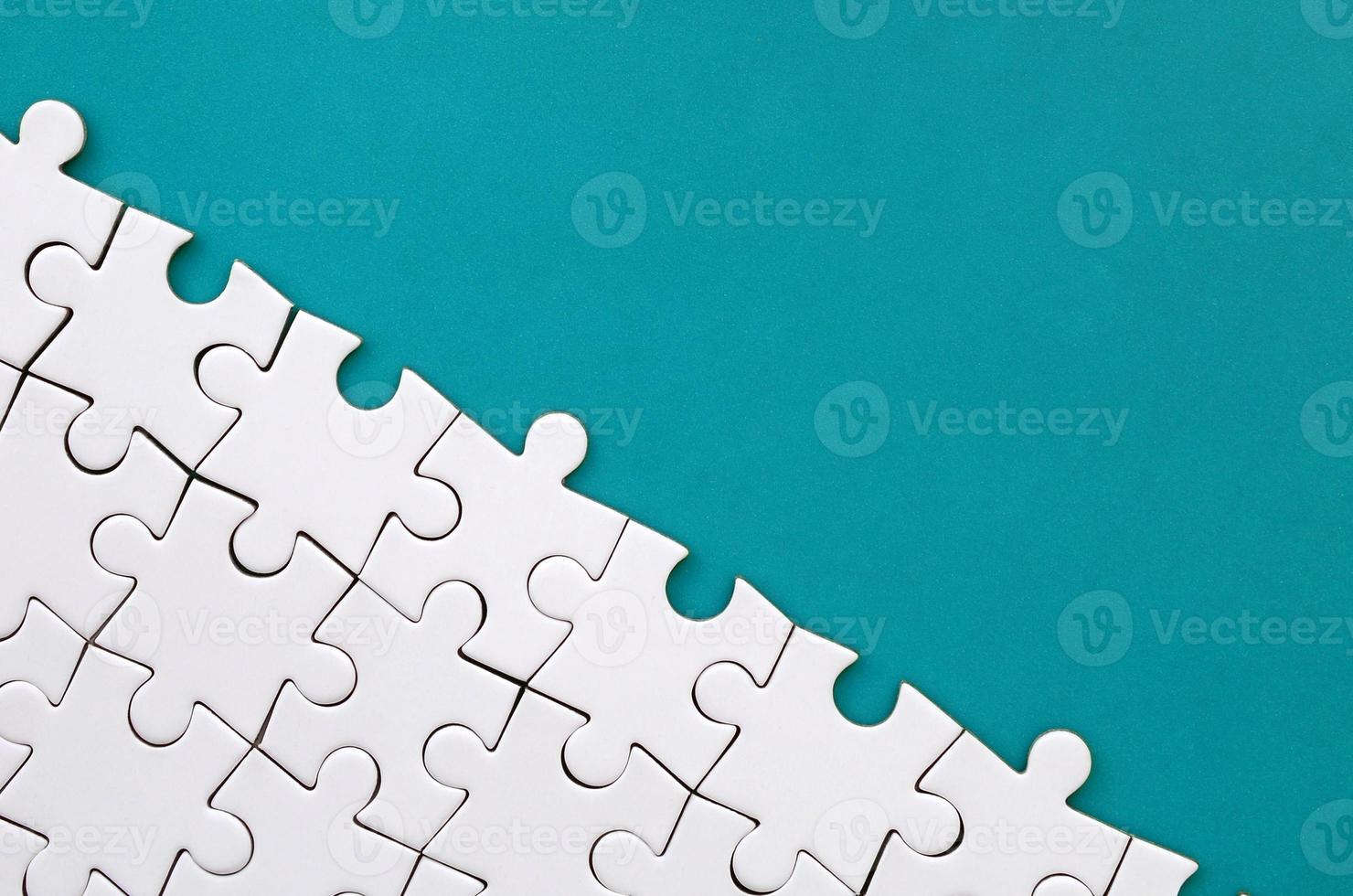 Fragment of a folded white jigsaw puzzle on the background of a blue plastic surface. Texture photo with copy space for text