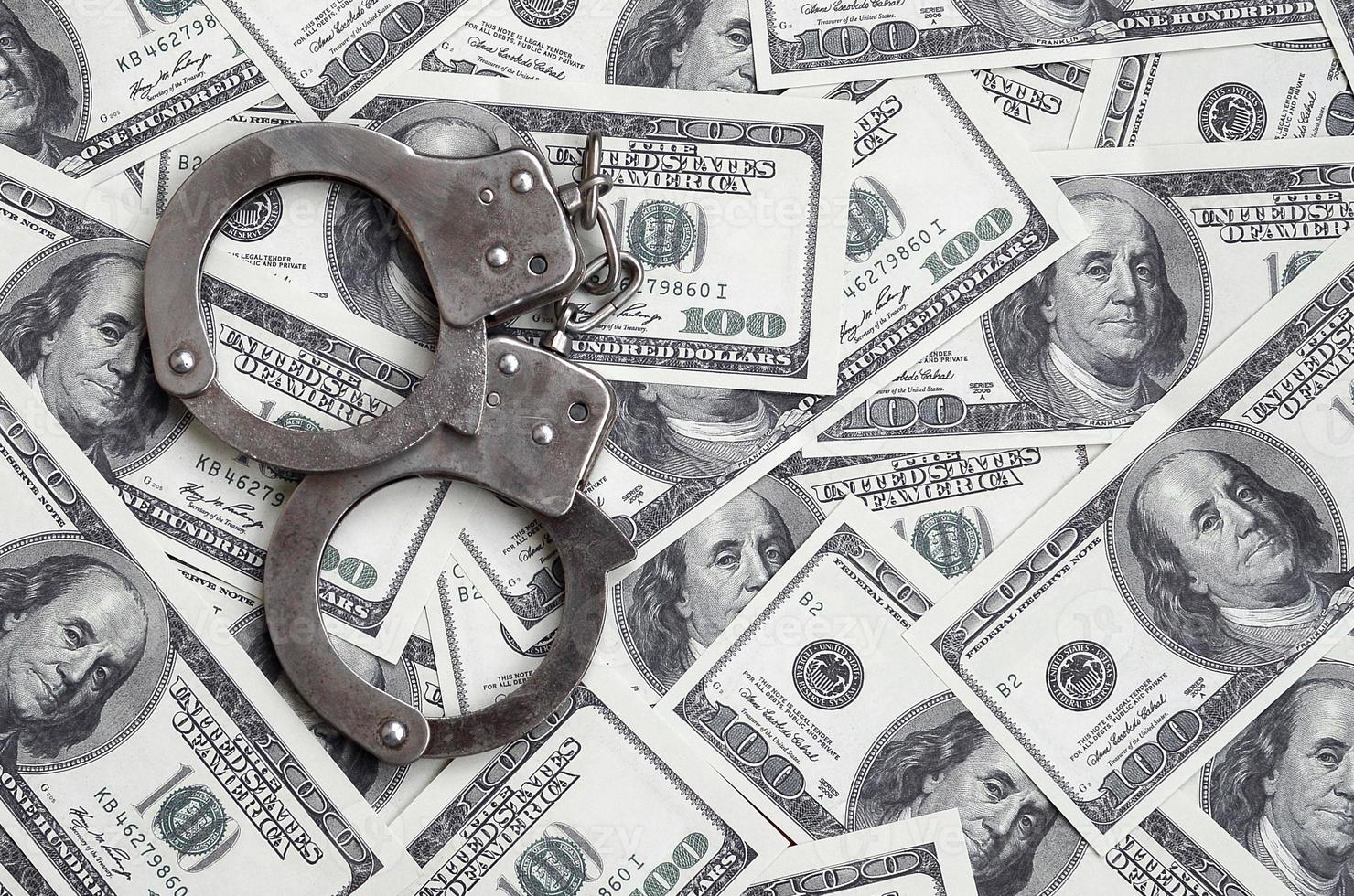 Police handcuffs lie on a lot of dollar bills. The concept of illegal possession of money, illegal transactions with US dollars. Economic Crime photo