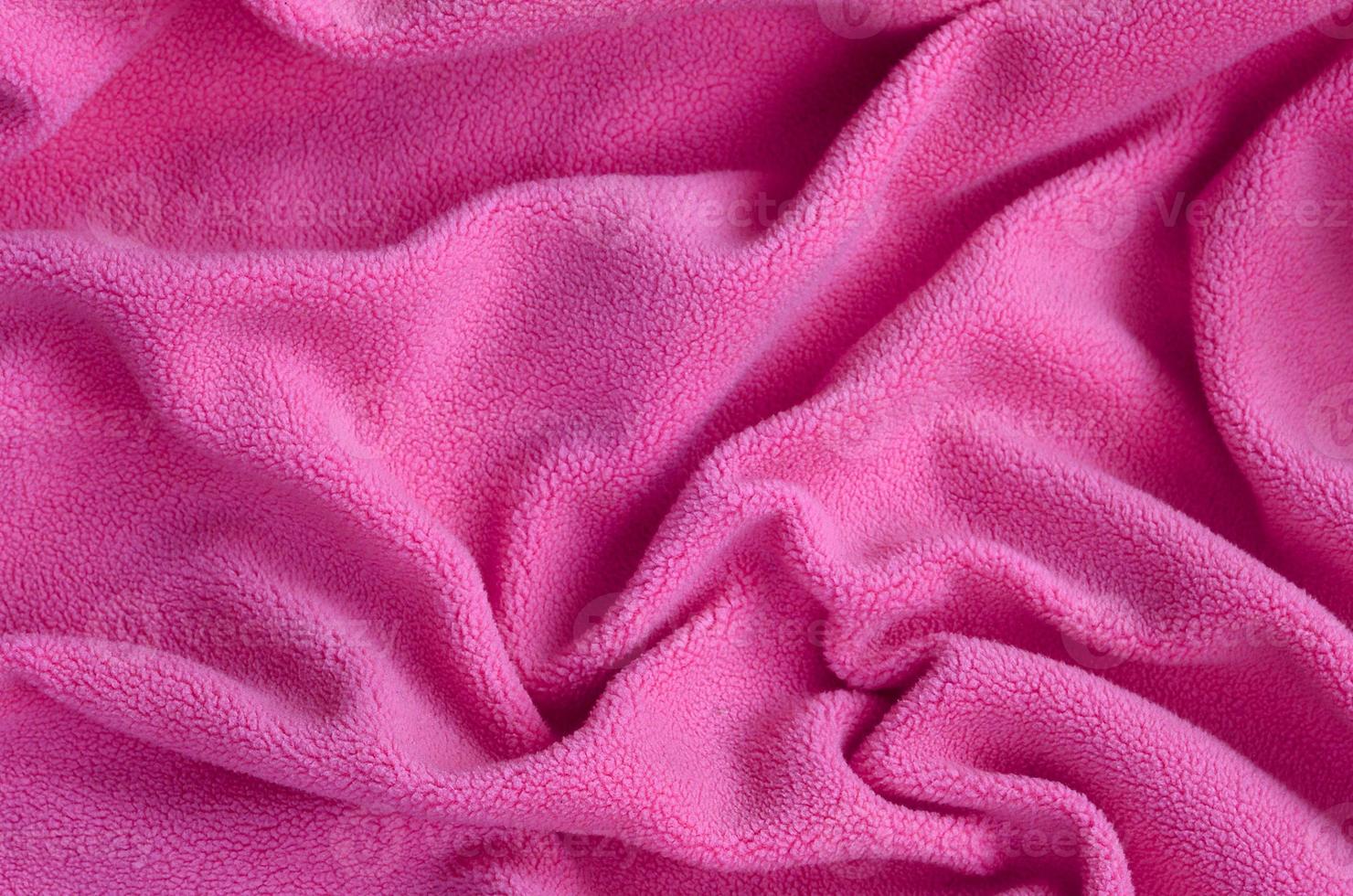 The blanket of furry pink fleece fabric. A background of light pink soft plush fleece material with a lot of relief folds photo