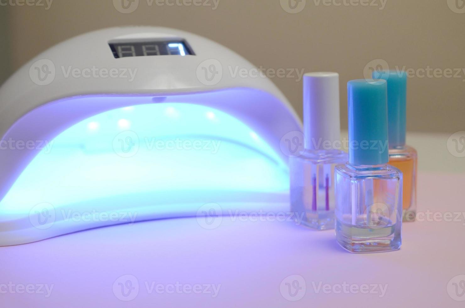 UV diode lamp lights for nails and set of cosmetic nail polish for manicure and pedicure on pastel background photo