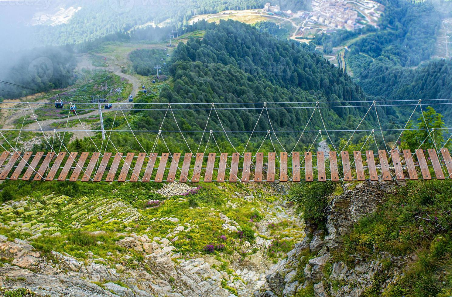 Suspended wooden bridge in the valley of the green mountains of the caucasus. Landscape photo